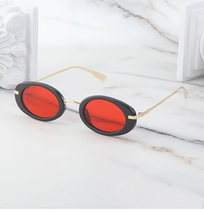 Dettaglio occhiali steampunk con lenti rosse ovali e stanghette in metallo dorato