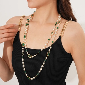 Detail of vintage multilayer pearl necklace with emerald green gemstone on a model