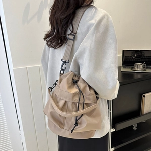 Sac seau en nylon kaki avec bandoulière ajustable porté par un mannequin en studio