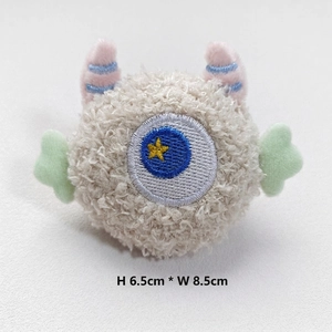 Detail of cute white plush monster brooch with blue star eye and sizing at 8.5x6.5cm