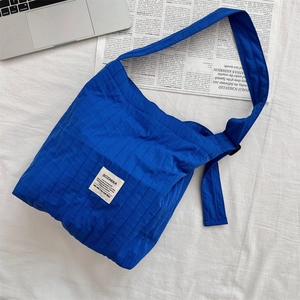 Detail of blue quilted pleated shoulder bag with adjustable strap and brand tag