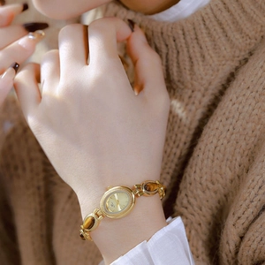 Close-up of a vintage gold tiger eye stone chain watch on a woman's wrist