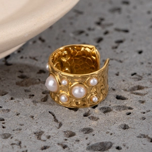 Hammered gold stainless steel open ring with embedded white pearls on a stone base