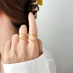 Close-up of double layered gold wave rings stacked on model's fingers in minimalist style