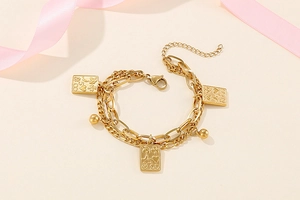 Close-up of golden double-layer chain bracelet with rectangular poker card charms