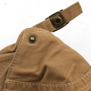 Close-up of adjustable strap on brown canvas beret with vintage bronze star buckle