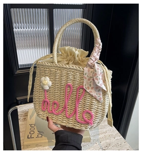 Detail of straw woven handbag with pink hello embroidery and floral scarf handle wrap