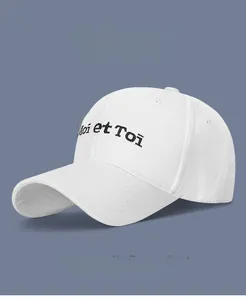 Close-up of white cotton baseball cap showing Moi et Toi embroidery and fine stitching
