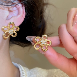 Close-up of golden flower stud earrings featuring zircon pavé center and hollow petals