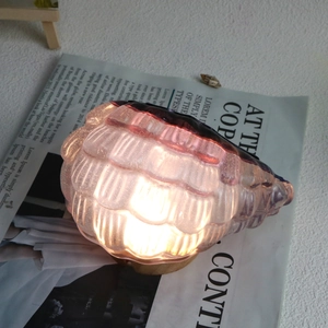 Vista dettagliata della lampada da tavolo in vetro a conchiglia con base in legno e luce viola