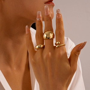 Detailed view of polished gold teardrop and minimalist dome rings on a model hand