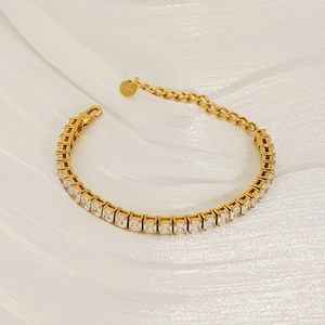 Detail of gold-plated stainless steel tennis bracelet with rectangular zircons on silk