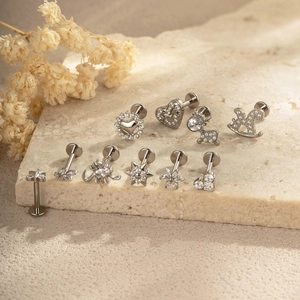 Titan G23 Labret-Set mit silbernen Herz- und Sterndesigns auf beigem Steinhintergrund