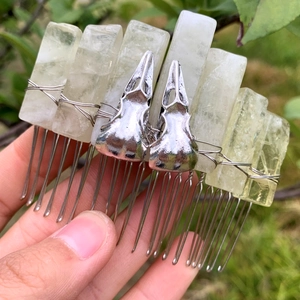 Detail view of natural crystal columns and silver skull charms on a handmade hair comb