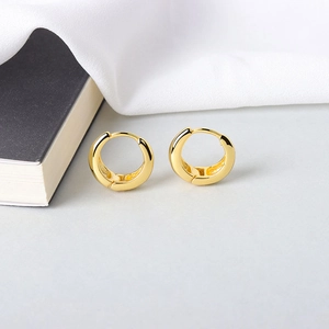 Minimalist S925 sterling silver hoop earrings in golden finish on a white fabric background