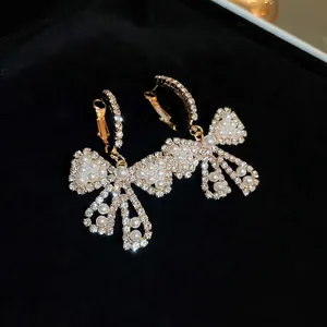 Elegant bow knot pearl drop earrings with sparkling rhinestones in gold luxury style