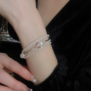Dettaglio del set di bracciali multistrato in argento con perle e strass lucidi