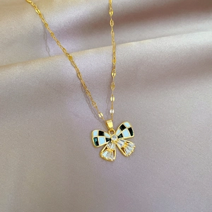 Détail du pendentif papillon doré avec émail à damier et zircones sur de la soie