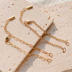 Detail einer goldenen Edelstahl-Büroklammerkette und Gliederkette mit Karabinern auf Stein