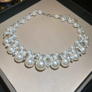 Detail of layered pearl necklace with sparkling rhinestones on a beige display tray
