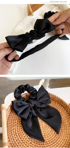 Close-up of black satin bow scrunchie with silky texture and long tail design