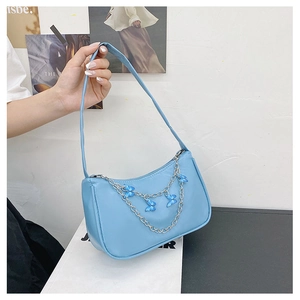 Detail of light blue shoulder bag with silver butterfly chain and smooth leather texture