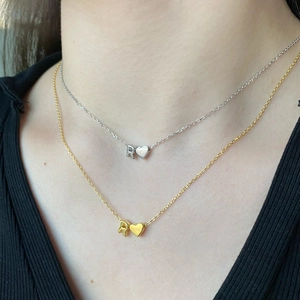 Close-up of S925 silver and gold heart pendant necklaces with letter R on a model