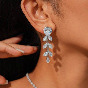 Close-up of elegant silver drop earrings with heart-shaped white zircon leaf-shaped accents
