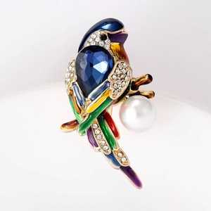Macro detail of bird brooch with blue gemstone, colorful enamel and white pearl