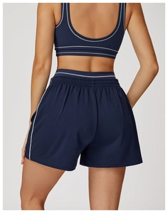 Dettaglio dei pantaloncini sportivi blu navy con profili bianchi a contrasto e vita alta