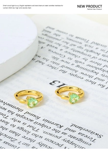 Detailed shot of golden heart-shaped zircon hoop earrings on a fashion magazine