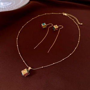 Detail view of gold 18K plated cat-eye stone necklace and earrings set on red velvet