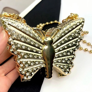 Close-up of luxury gold butterfly evening bag with shimmering rhinestones and chain strap