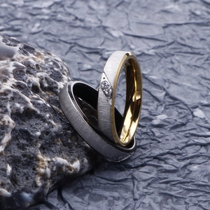 Close-up of brushed stainless steel couple rings with diamond accents on stone base