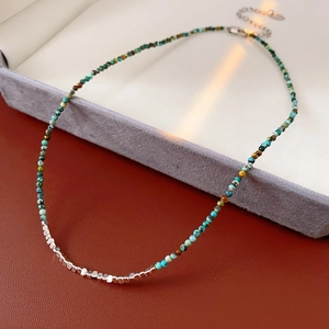 Detail of beaded necklace with blue stones, silver square beads, and lobster clasp