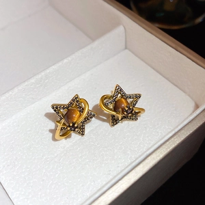 Macro view of vintage gold star planet stud earrings with black zircon and cat's eye stone