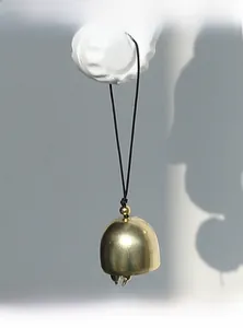 Close-up of golden metal bell with black hanging cord and elegant matte finish