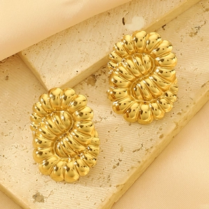 Elegant gold geometric ripple earrings on stone with a wavy texture and silk background