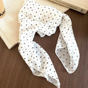Close-up of white polka dot scarf on a vintage wooden table with art book background