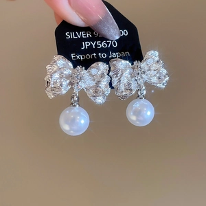 Vue macro de boucles d'oreilles nœud en argent 925 avec perles rondes et effet brillant