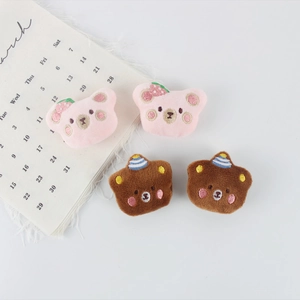 Detail of plush bear brooches featuring pink strawberry and brown party hat designs