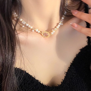 Detail of elegant double-layered necklace with faux pearls and pink gemstone pendant
