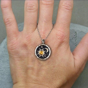 Detail of sun and moon pendant necklace with yellow gemstone on a hand model