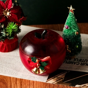Détail d'une boîte en résine en forme de pomme avec nœud festif et cloches dorées sur bois