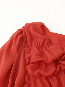 Close-up of ruched coral chiffon fabric detailing the intricate stitching and pleated texture