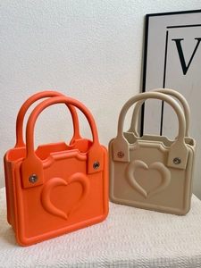 Detail view of bright orange and beige EVA beach bags with embossed heart design