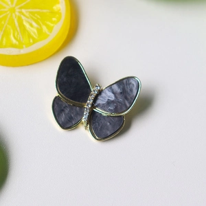 Detailed view of butterfly brooch with gold frame and grey marble textured wings