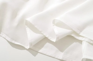 Detailed macro view of white fabric texture with professional stitching on the dress hem