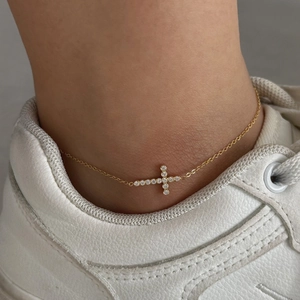 Gold stainless steel anklet with zircon cross pendant worn on ankle with white sneakers
