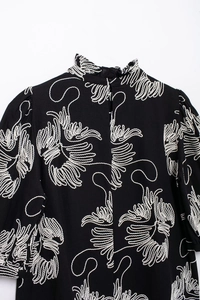 Close-up of elegant white embroidery on the collar of a black short sleeve blouse